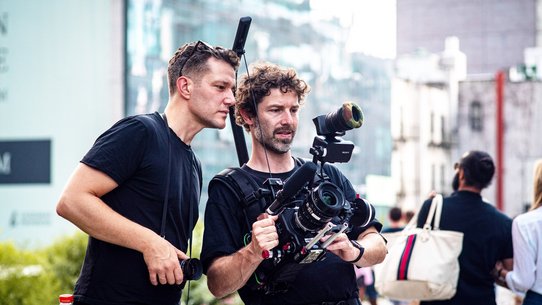 Regisseur Max Langfeldt (links) schaut bei einer Filmproduktion dem Kameramann über die Schulter.